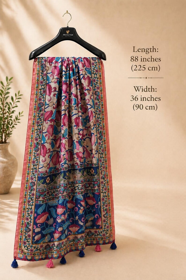 Puede incluir: Bufanda decorativa con estampado floral en tonos rosa, azul y beige, colgada de una percha negra. La bufanda mide 225 cm de largo y 90 cm de ancho, con borlas. El texto indica las dimensiones.