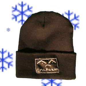 Può includere: Berretto nero con una toppa ricamata bianca che dice "GMCFOSKMO" e ha una faccia triste con sopracciglia.