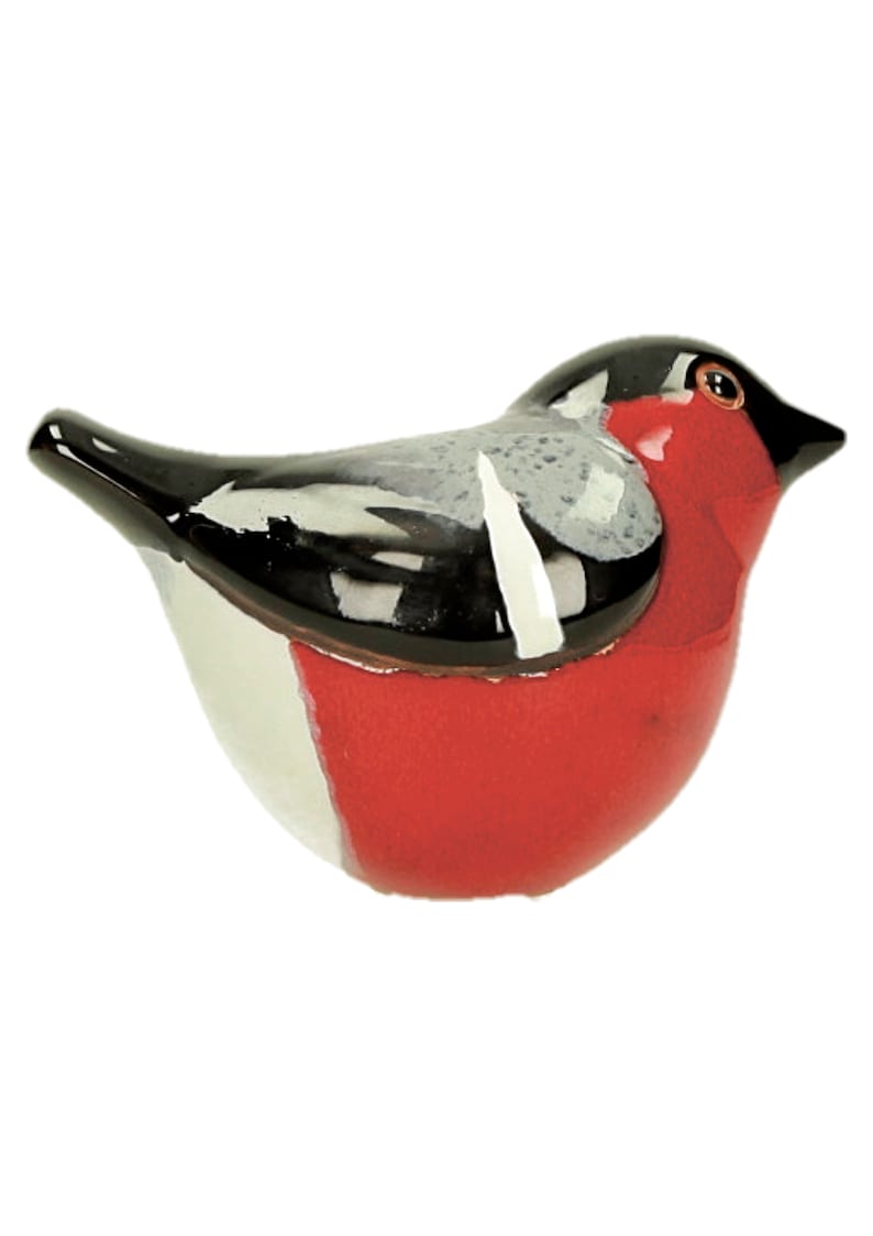 May include: A ceramic bird figurine with black, white, and red paint. The bird has a round body and a short beak.