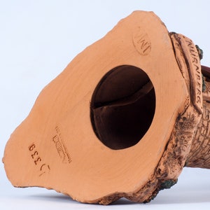 May include: A terracotta figurine of a house with a thatched roof and a chimney. The figurine is hand-painted with brown, green, and white details. The bottom of the figurine is stamped with "NURNBERG" and "INI" in a circle.