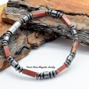 Puede incluir: Un brazalete magnético rojo y negro con el texto "Power Stone Magnetic Jewelry".