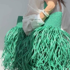 Stor sommarväska, strandväska, shoppingväska, tygväska, med fransar, tillverkad av naturlig raffia, ett trendigt accessoar.