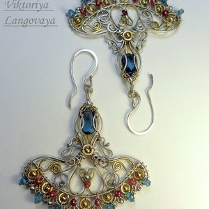 May include: A pair of silver and gold earrings with blue and red gemstones. The earrings are in the shape of a fan with a large blue gemstone in the center. The text "jewelry by Viktoriya Lanzovaya" is visible in the top left corner of the image.
