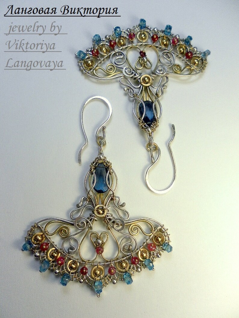 May include: A pair of silver and gold earrings with blue and red gemstones. The earrings are in the shape of a fan with a large blue gemstone in the center. The text "jewelry by Viktoriya Lanzovaya" is visible in the top left corner of the image.