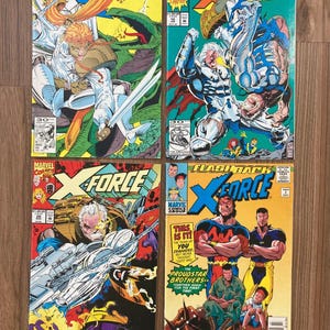 May include: Four vintage X-Force comic books are displayed. The covers feature action-packed illustrations with characters in dynamic poses. Bold colors and text, including "X-Force" and "Marvel Comics," are prominent. The comics are from the 90s.