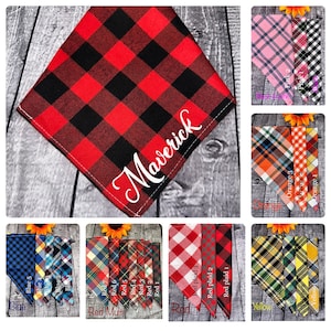May include: A collection of dog bandanas in various plaid patterns, including red, blue, orange, yellow, and pink. The bandanas are arranged in rows, with each row representing a different color. The bandanas are all made of cotton fabric and have a personalized name embroidered on them. The name "Maverick" is embroidered on one of the bandanas.