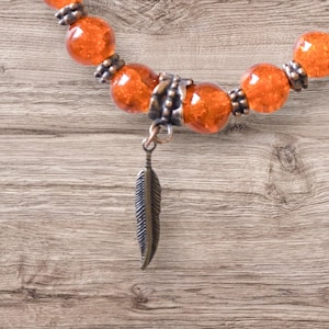 Armband 'Elk Kind Doet ertoe' met oranje craqueléglas en koperen veer - Donatie aan IRSSS