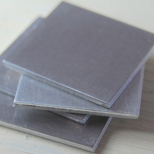May include: A stack of four silver metal squares.