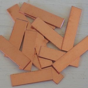 May include: A pile of 15 thin, rectangular copper sheets. The sheets are a warm, reddish-brown color and have a slightly textured surface.