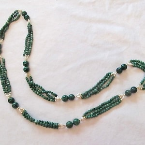 Puede incluir: Un collar de múltiples hilos hecho de cuentas de jade verde con detalles plateados.
