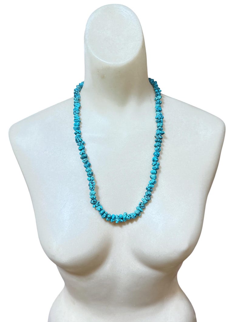 Puede incluir: Un collar de una sola hebra compuesto por numerosas cuentas de turquesa peque&ntilde;as, irregulares y pulidas. Las cuentas presentan un color azul cian vibrante con patrones de matriz oscuros en forma de red en toda su superficie.
