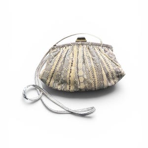 May include: A vintage handbag with a snakeskin pattern in cream, grey, and brown. The bag has a rounded shape with a clasp closure and a silver shoulder strap. The handle is also silver.