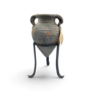 May include: A textured, dark gray ceramic vessel with two side handles and a pointed base, featuring geometric patterns in muted blue and brown tones. The vessel is supported by a black metal tripod stand and includes a small paper tag.