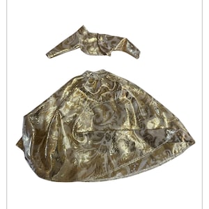 Puede incluir: Un conjunto de capa y bolero dorados. La tela tiene un patrón texturizado y arremolinado. El bolero es una chaqueta corta y recortada, y la capa es una prenda completa y fluida. El conjunto es probablemente para un disfraz u ocasión especial.