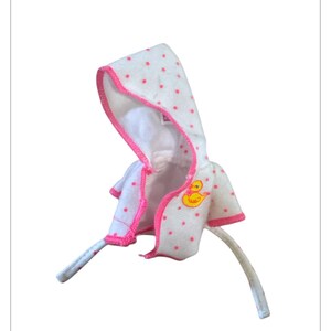 May include: White baby bath towel with a hood, pink polka dots and trim. It has a yellow duck graphic. Includes two long ties. A soft and cosy accessory for after bath time.