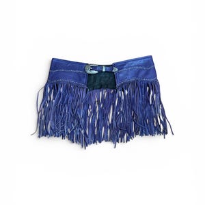 May include: A blue leather fringe belt with a silver buckle and studded details. The belt features long, flowing fringe and is designed to be worn around the waist. The belt's colour is a deep shade of blue, and the fringe adds a dynamic element.