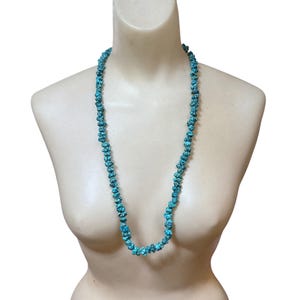 Puede incluir: Un collar largo compuesto por numerosas piedras peque&ntilde;as, irregulares y pulidas de color turquesa. Las cuentas presentan un tono azul verdoso vibrante con patrones de matriz oscuros similares a una red, ensartadas en una sola hebra.