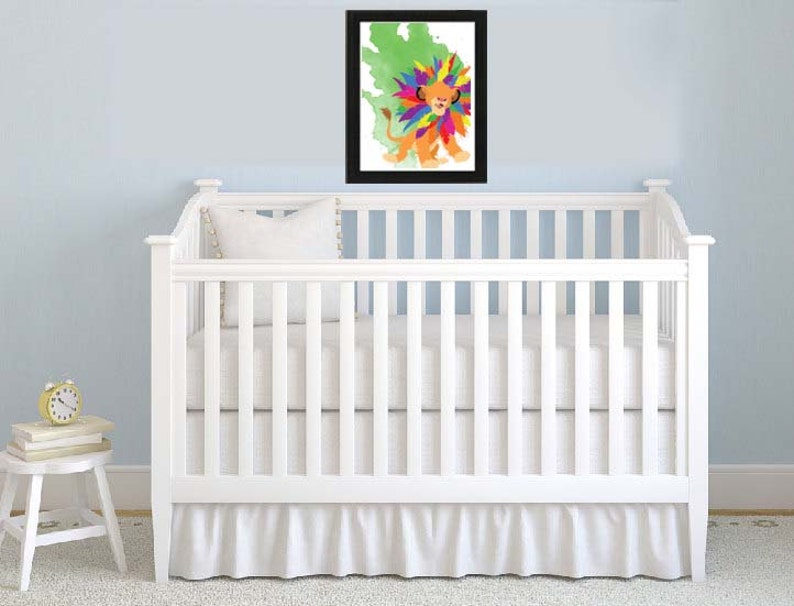 May include: A white crib with a white ruffle skirt and a framed print of a colorful lion with a green background.