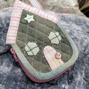 May include: A small green and pink house-shaped zippered pouch with a star and button accents.