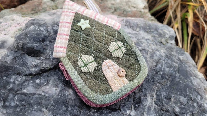 May include: A small green and pink house-shaped zippered pouch with a star and button accents.