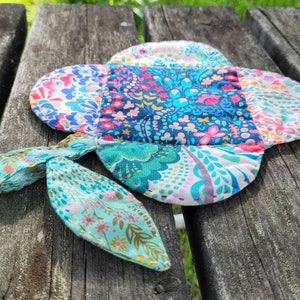Pu&ograve; includere: Un sottopentola in tessuto patchwork colorato con un motivo floreale. Il sottopentola ha un'ansa a forma di anello ed &egrave; realizzato in tessuto di cotone.