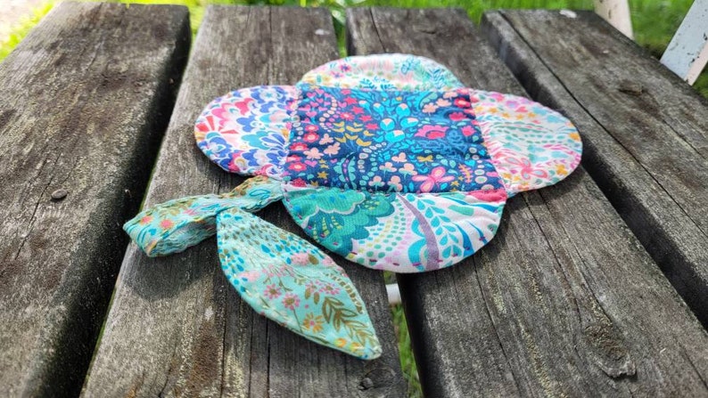 Pu&ograve; includere: Un sottopentola in tessuto patchwork colorato con un motivo floreale. Il sottopentola ha un'ansa a forma di anello ed &egrave; realizzato in tessuto di cotone.