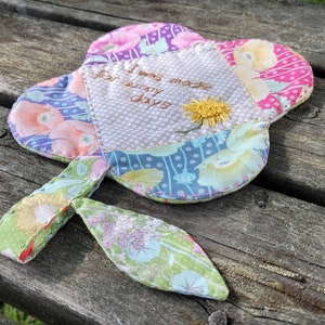 Pu&ograve; includere: Un fiore di stoffa colorato con uno stelo, ricamato con il testo "Sono stato fatto per le giornate di sole".