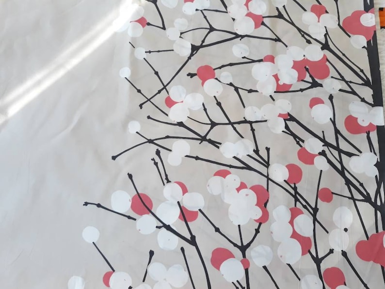 Puede incluir: Una tela blanca con un patr&oacute;n floral negro y rosa. El patr&oacute;n presenta ramas estilizadas con c&iacute;rculos blancos y rosas.