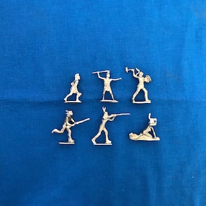 May include: Set of seven silver toy soldiers, each with a different pose and weapon. The soldiers are standing on a blue surface.