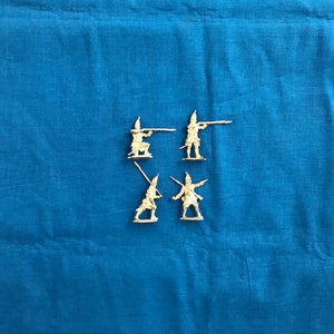 May include: Five miniature plastic figures of soldiers holding rifles and swords. The figures are painted in a light brown color and are posed in various action stances.
