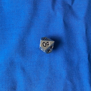 Peut inclure: Un dé d20 en métal argenté avec des chiffres noirs, montrant un résultat de 19.
