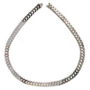 May include: A silver chain necklace with a curb link design