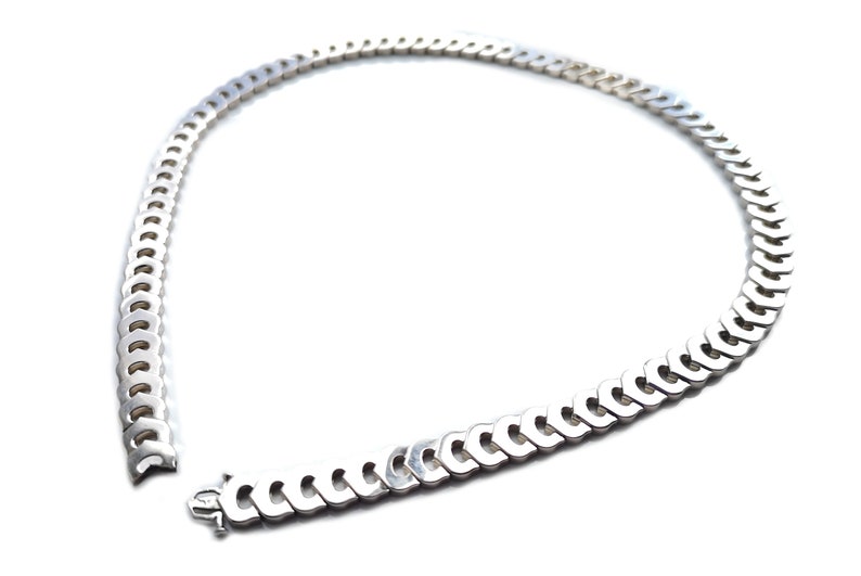May include: A silver chain necklace with a curb link design. The chain is open and the ends are visible.