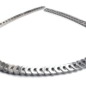 May include: A silver chain necklace with a unique link design. The links are shaped like a series of connected ovals.