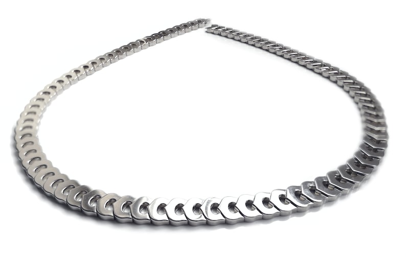 May include: A silver chain necklace with a unique link design. The links are shaped like a series of connected ovals.