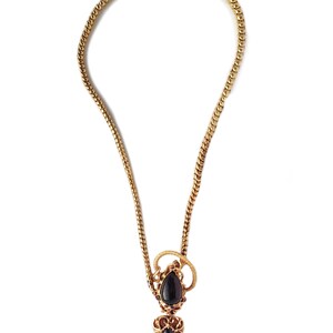 May include: A gold chain necklace with a pendant featuring two black gemstones set in a gold filigree design.