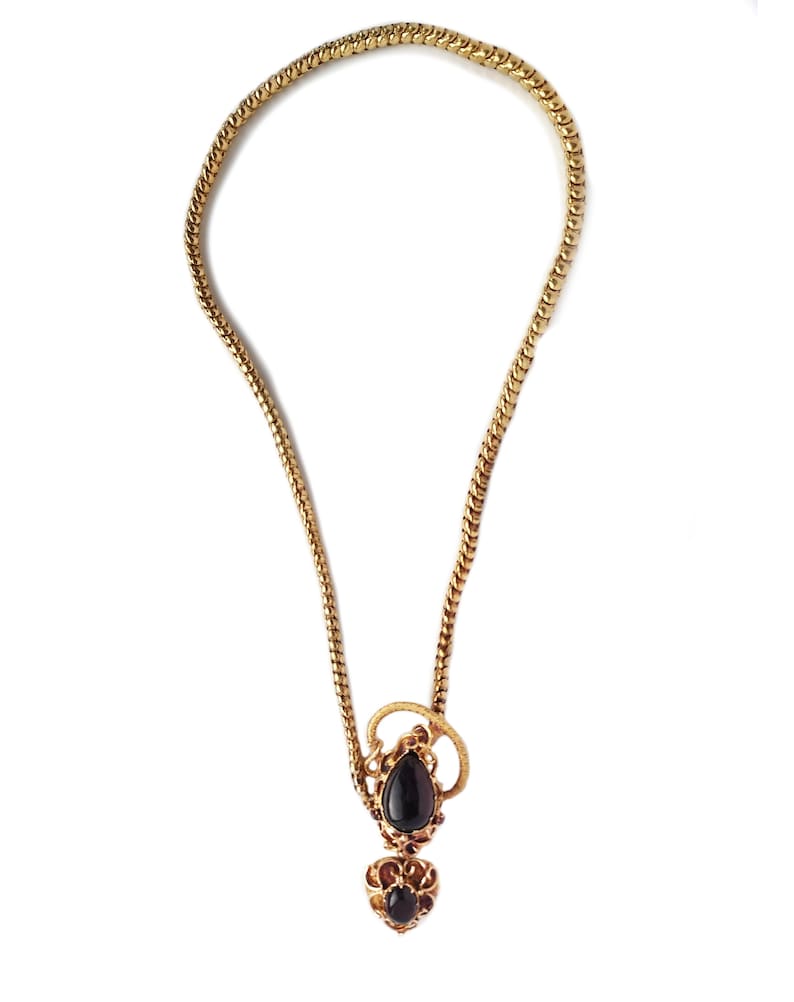 May include: A gold chain necklace with a pendant featuring two black gemstones set in a gold filigree design.