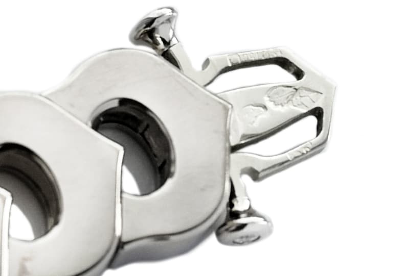 May include: Close-up of a silver metal bracelet clasp with a detailed design. The clasp has two screws and a small engraved design that includes the words '925 Italy'.