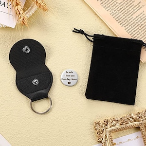 May include: A silver keychain with a black leather pouch and a round metal charm that reads "Be safe I love you One day closer".