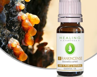 Könnte beinhalten: Eine kleine bernsteinfarbene Glasflasche mit weißem Verschluss, beschriftet mit "Frankincense Boswellia carterii 100% reines & natürliches ätherisches Öl". Die Flasche steht auf einem weißen Hintergrund mit einer Nahaufnahme des harzigen Weihrauchs.