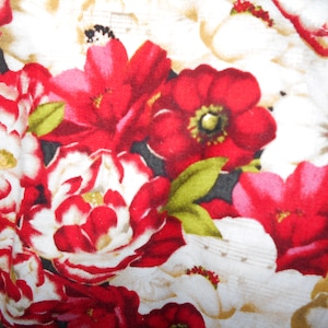 May include: A white fabric with a red and white floral pattern. The flowers are large and have a lot of detail. The fabric is soft and has a smooth texture.