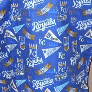 May include: Blue fabric with a repeating pattern of gold crowns, baseball bats, and the words "Kansas City Royals" in white and gold lettering.
