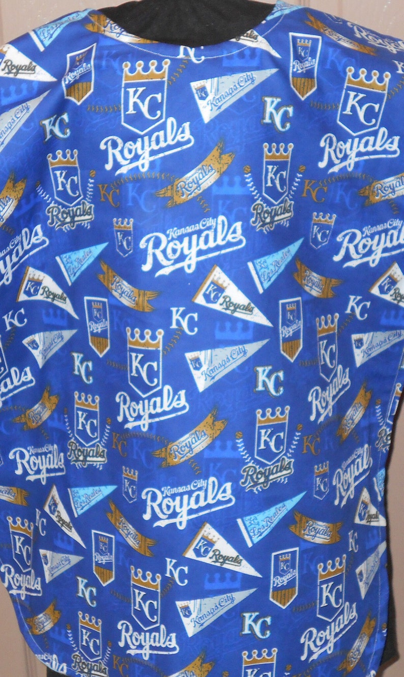 May include: Blue fabric with a repeating pattern of gold crowns, baseball bats, and the words "Kansas City Royals" in white and gold lettering.