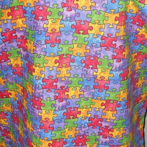 May include: A colorful fabric with a repeating pattern of puzzle pieces in shades of red, blue, green, yellow, and purple.