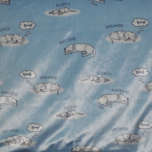 May include: A blue fleece blanket with a repeating pattern of white sleeping dogs and the words "Sleepy", "Dreamer", and "Naptime".