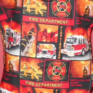 May include: A red, black, and white fabric with a repeating pattern of fire trucks, firefighters, and the words "Fire Department" and "Fire Fighters".