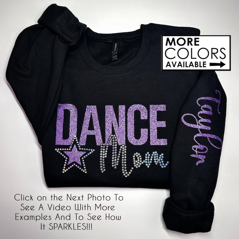May include: Black sweatshirt with purple glitter text that reads "DANCE MOM" with a star above the "M". The right sleeve has the name "Taylor" in glitter text. The text "MORE COLORS AVAILABLE" is in the top right corner of the image.