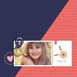 May include: A scrapbook page with a photo of a young girl smiling. The page is decorated with a gold ampersand, a pink heart, and a floral design. The text "LOVE THIS MEMORY OF US" is written on the page.