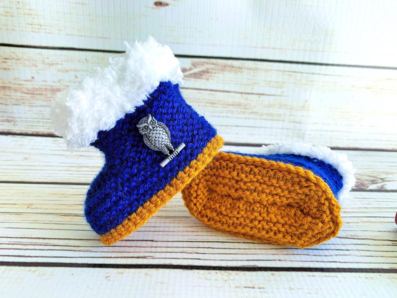 May include: A pair of handmade crochet baby booties. The booties are blue with a white fluffy trim and a silver owl embellishment. The soles are mustard yellow. A cozy and unique baby gift.