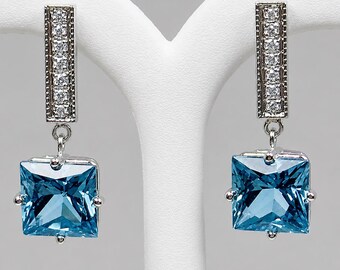 3.12 carats Blue Topaz dangle earrings in 14 k white gold.  Accented with .14 carats of diamonds.